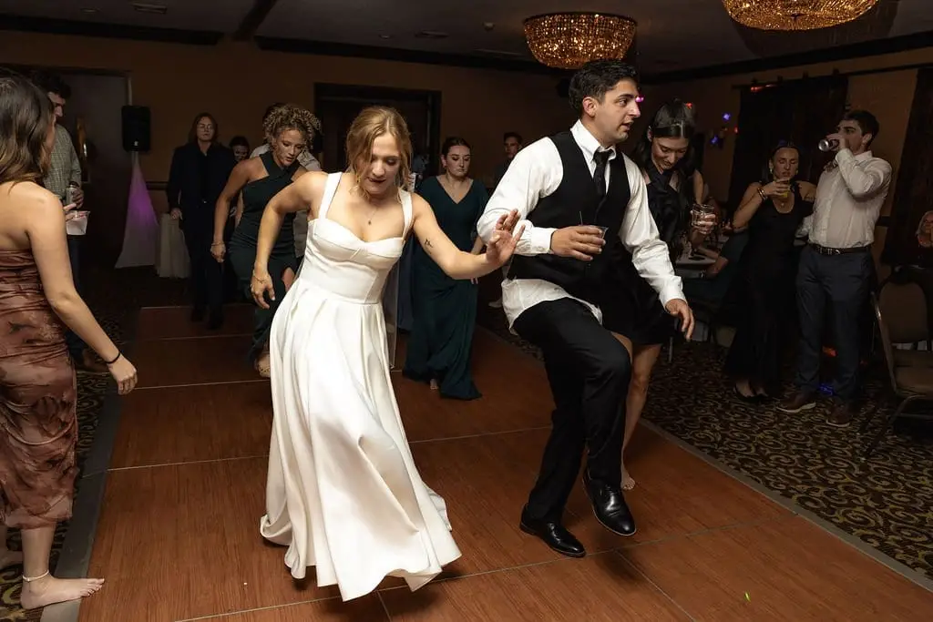 Bride and groom dancing mid-step on the reception dance floor as guests watch