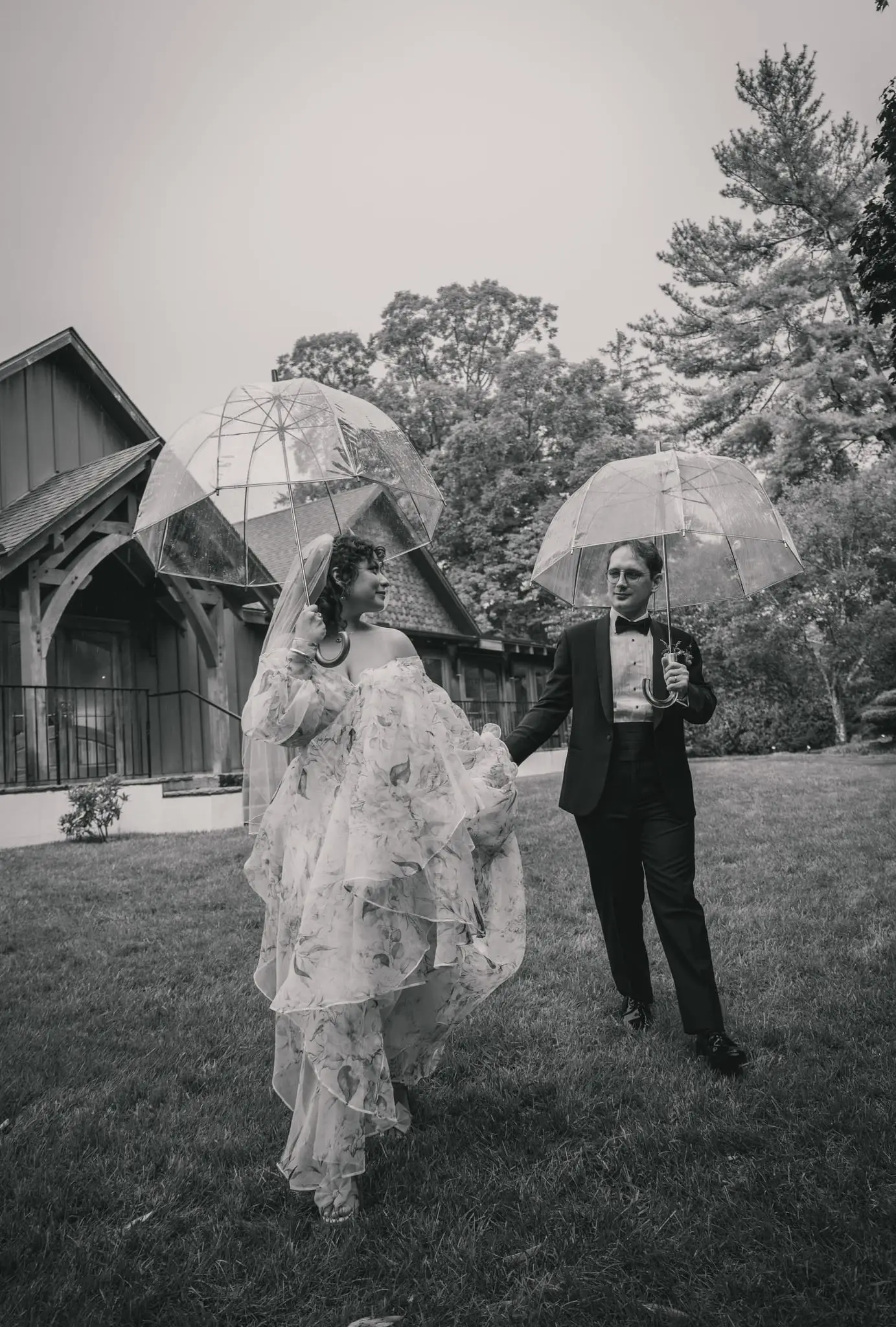 Bride in a floral gown kissing her groom among the trees at Weaver House