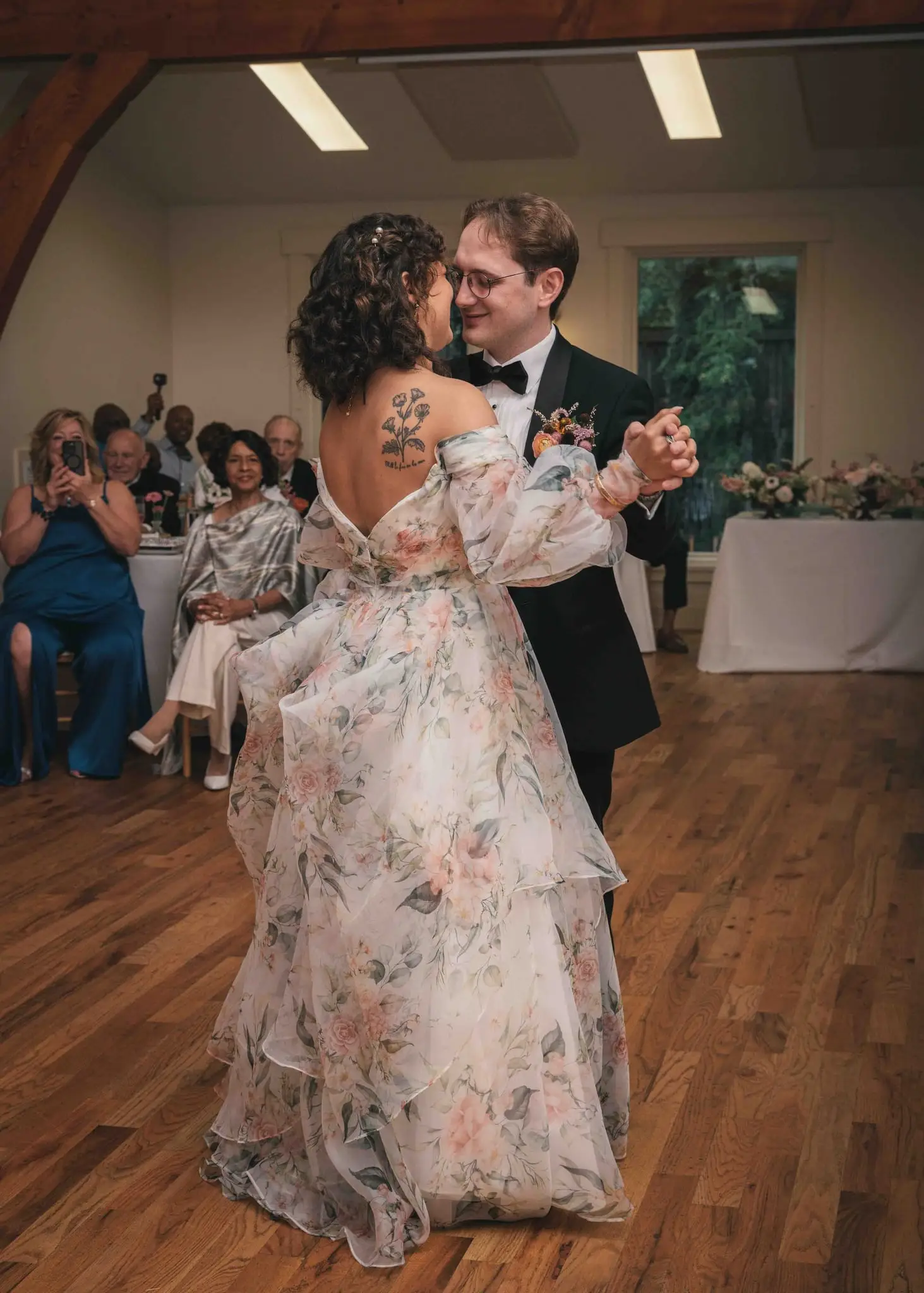 Maya and Jeff wedding at Weaver House, Weaverville NC — the couple dancing on a wood floor with guests seated at tables behind them