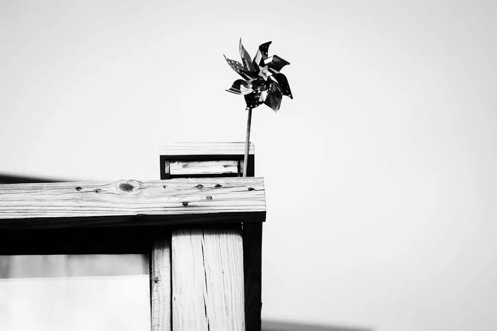 Black and white pinwheel spinning on a wooden post against a bright sky