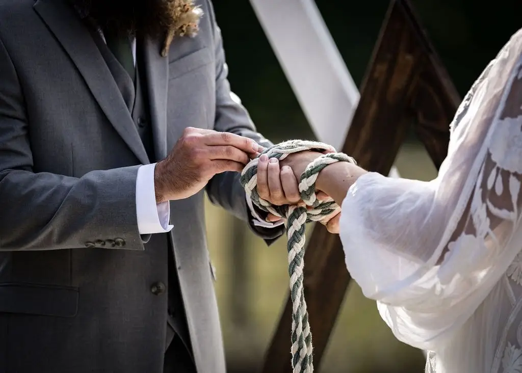 Hands bound with a green and white rope during the handfasting ceremony