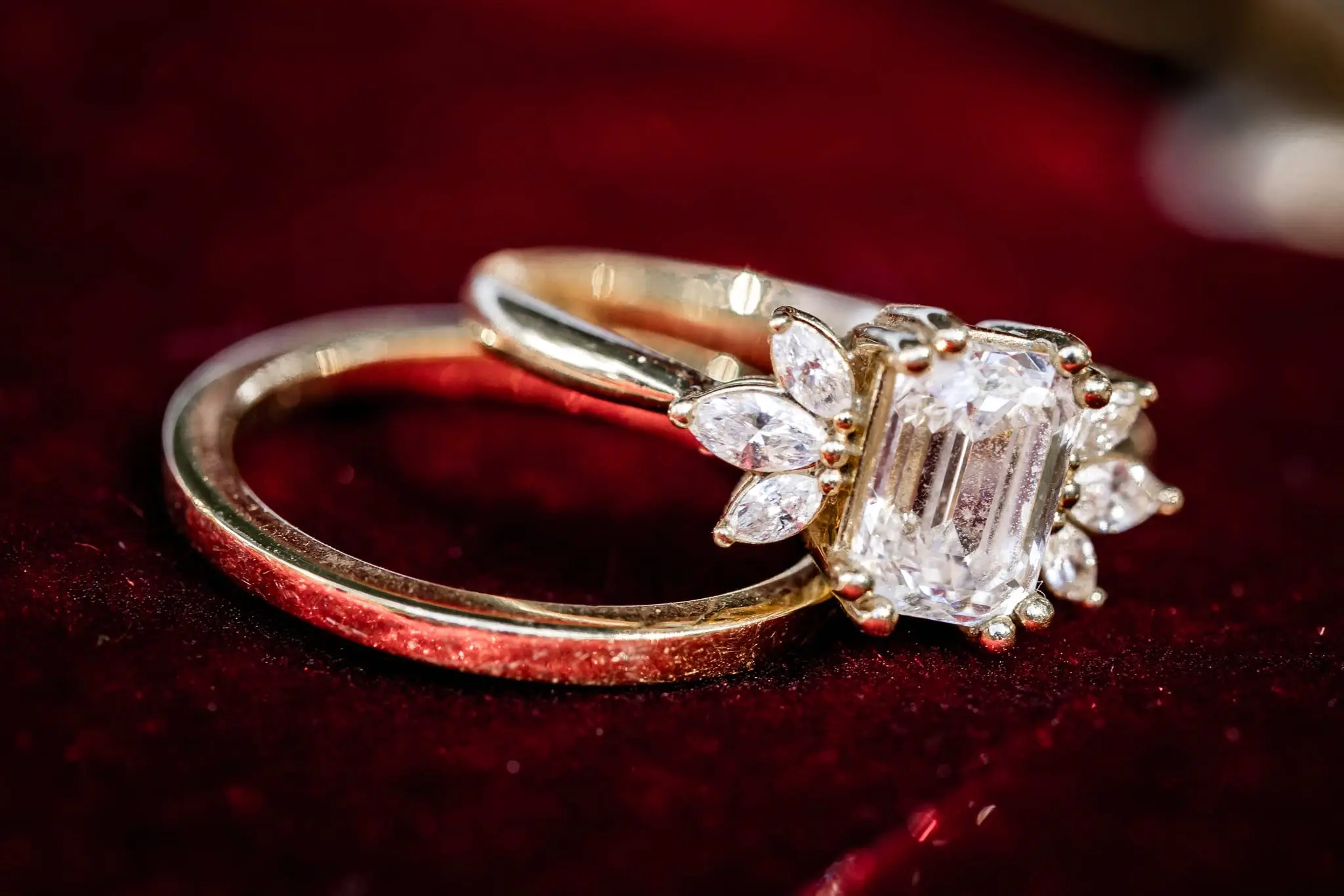 Diamond engagement ring with marquise side stones stacked on a gold band against red velvet
