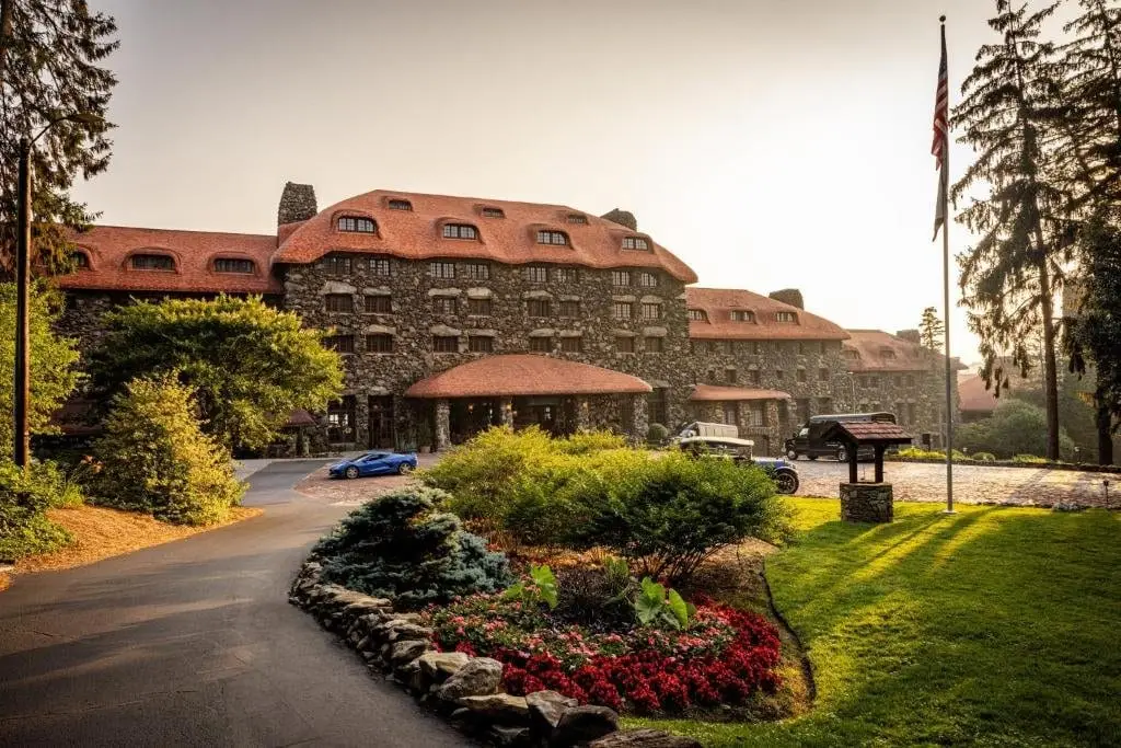 Omni Grove Park Inn's stone facade and red tile roof glowing at sunset over landscaped gardens