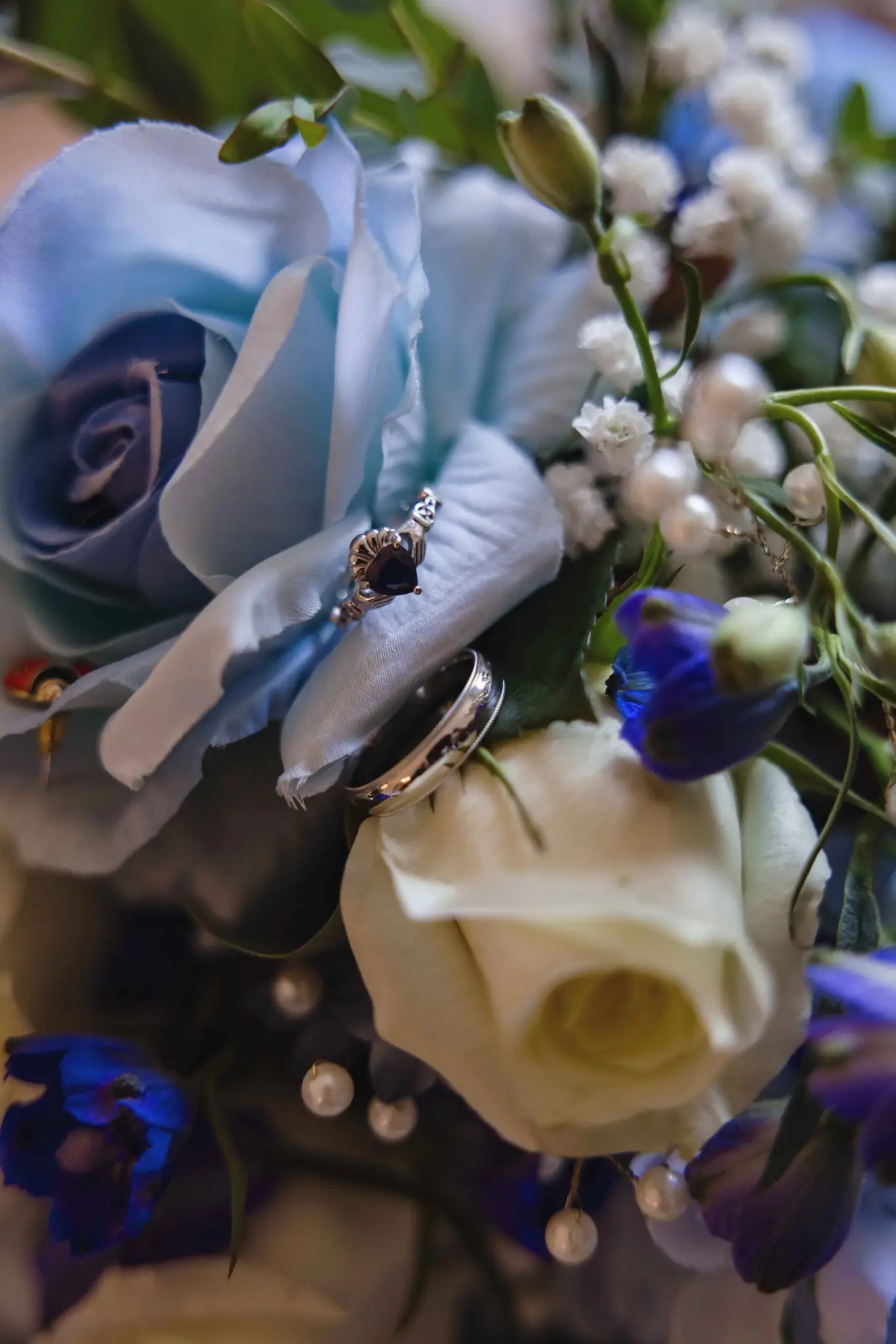 Wedding rings resting on a bouquet of blue and white roses