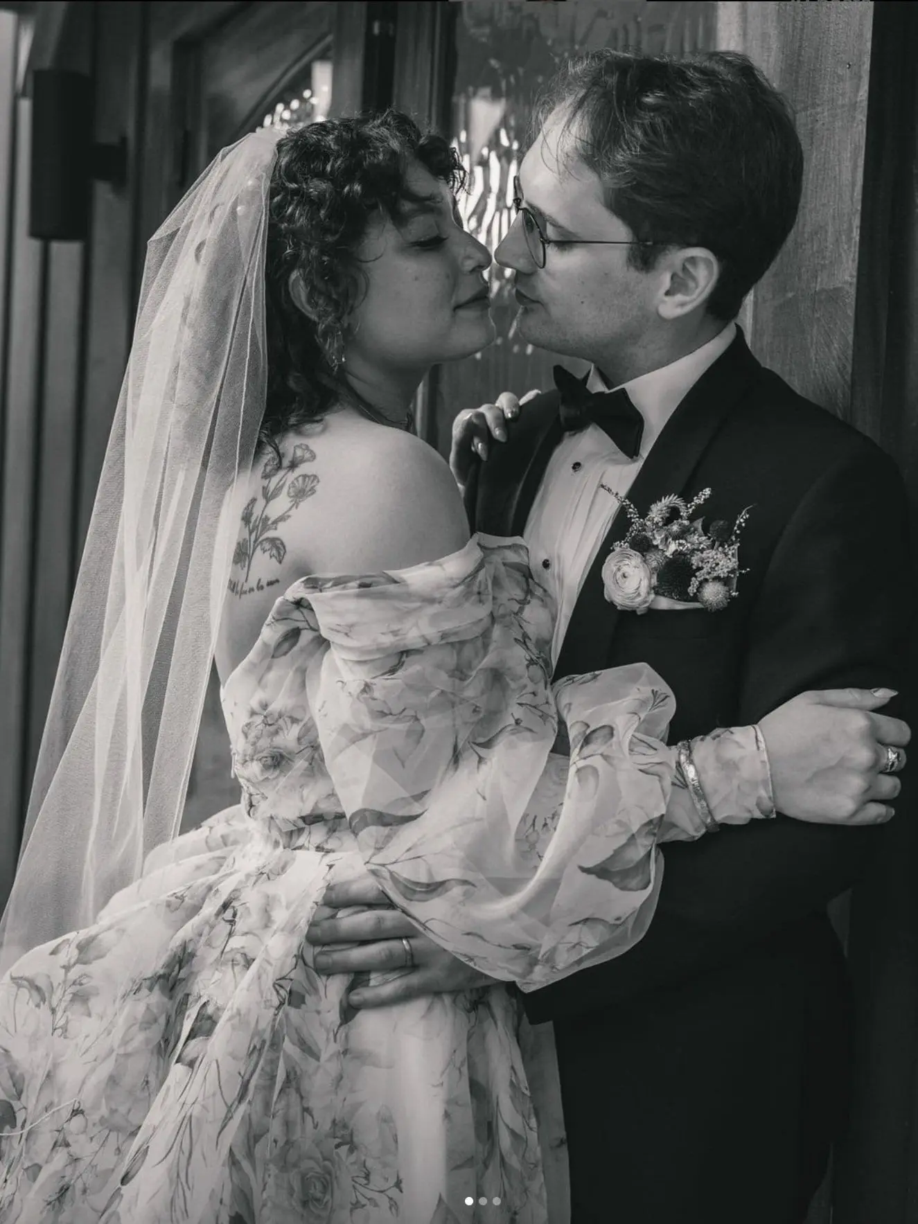 Black and white of a bride and groom nose to nose, her veil and puffed sleeves framing the moment