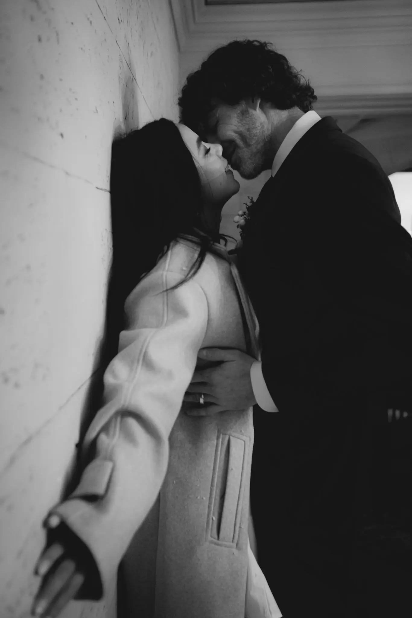 Black and white of a couple kissing against a stone wall after their courthouse wedding