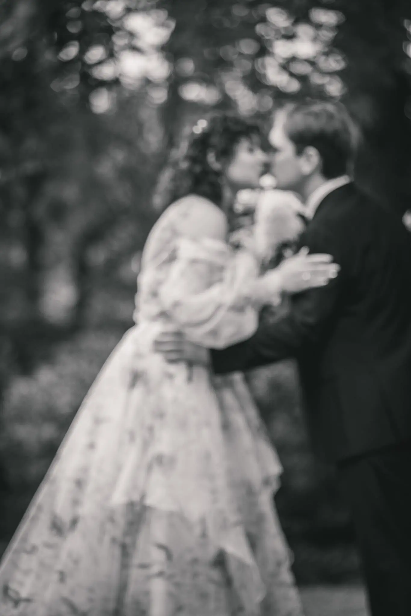 Black and white dip kiss in the bride's flowing floral gown in a garden at Weaver House