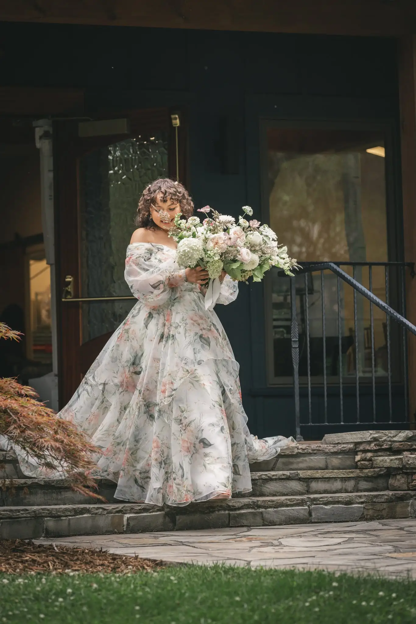 Maya and Jeff wedding at Weaver House, Weaverville NC — the bride in a floral gown with a bouquet at the top of stone steps